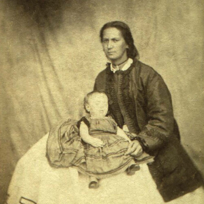 Historic black and white photo of Jane Clendon sitting for a portrait holding an infant