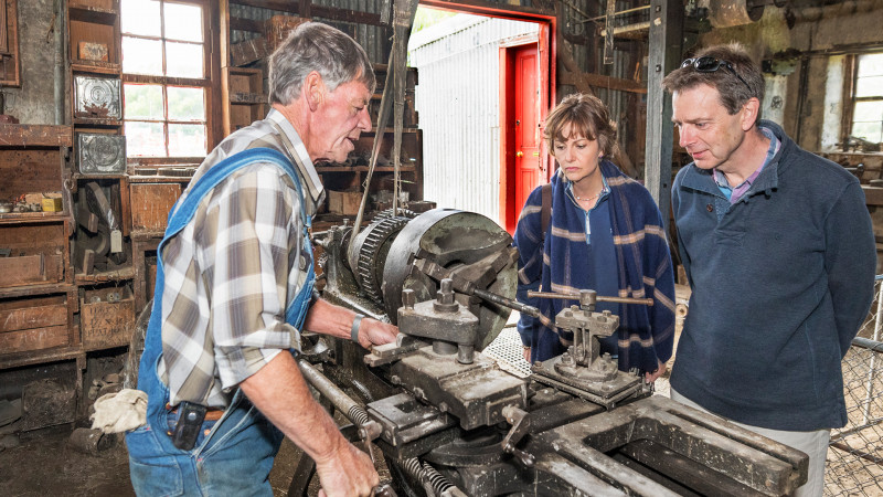 A staff member showing a man and a woman some equipment in the Hayes workshop