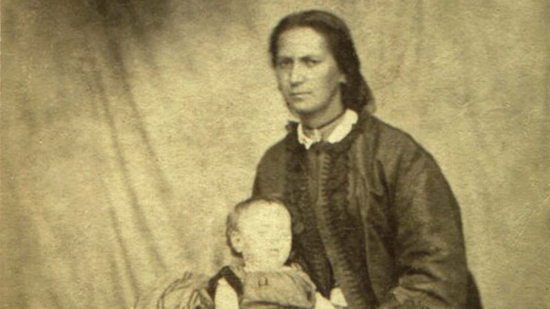 Historic black and white photo of Jane Clendon sitting for a portrait holding an infant