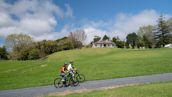 Couple cycling up the hill to Māngungu Mission house
