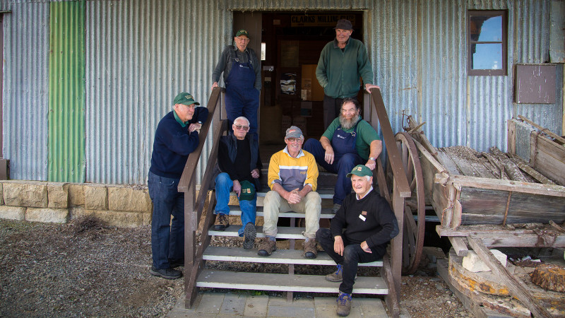 Seven male volunteers sit on the stairs at the entrance to the mill