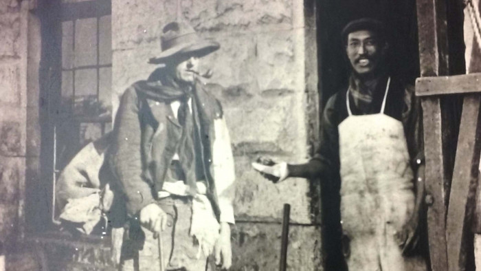 Historic black and white photo of Jimmy Hoey the cook standing in the door of the cookhouse passing food to a swagger