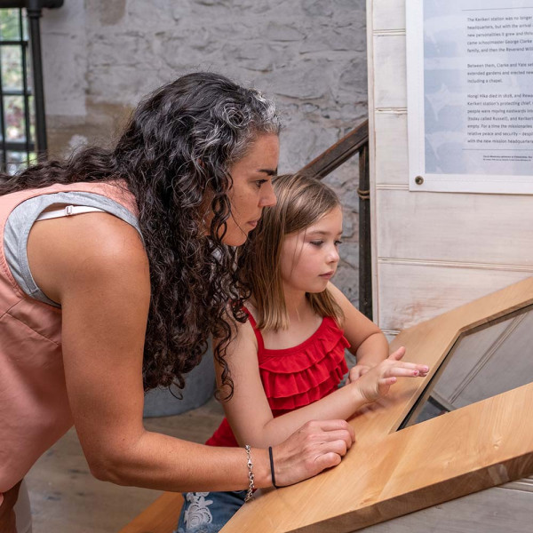 Mother and daughter engaging with digital heritage on a touch screen.