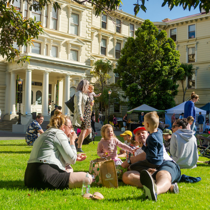 A family enjoying some food on the lawns at an event outside Old Government Buildings
