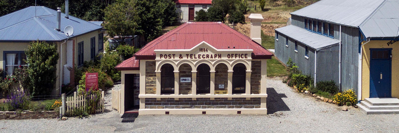 Ophir Post Office building made of unworked schist slabs with a touch of square pointing on the formal façade, concrete pillars and arched arcade