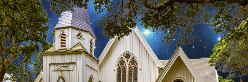 Exterior image of the front of an old wooden church with starry night sky in the background.